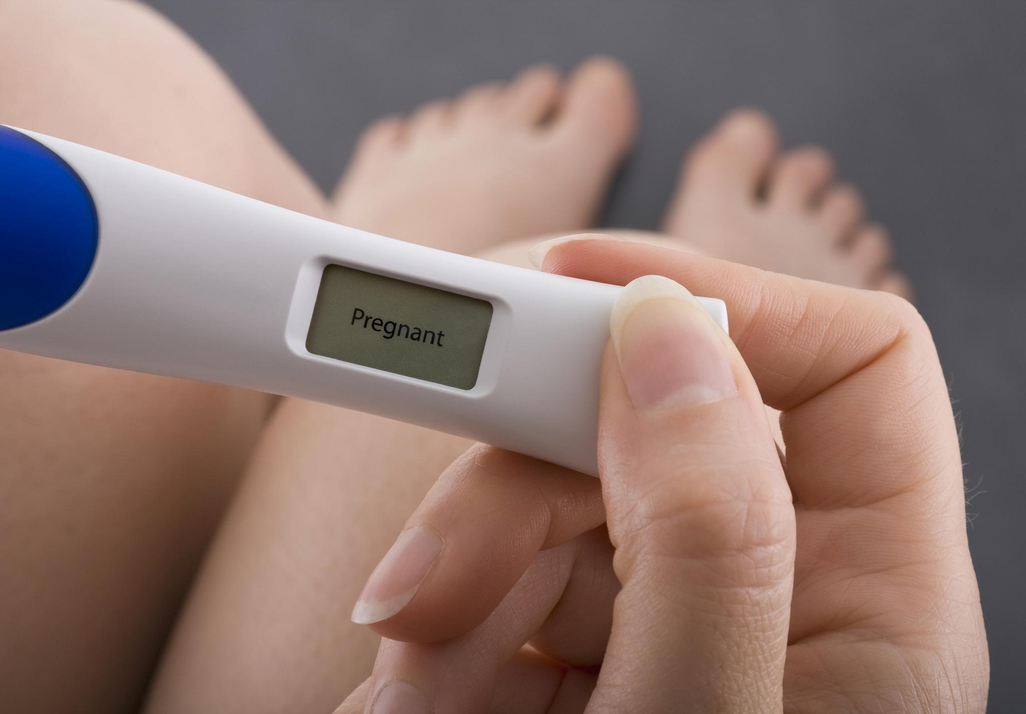 Donna in piedi guarda test di gravidanza