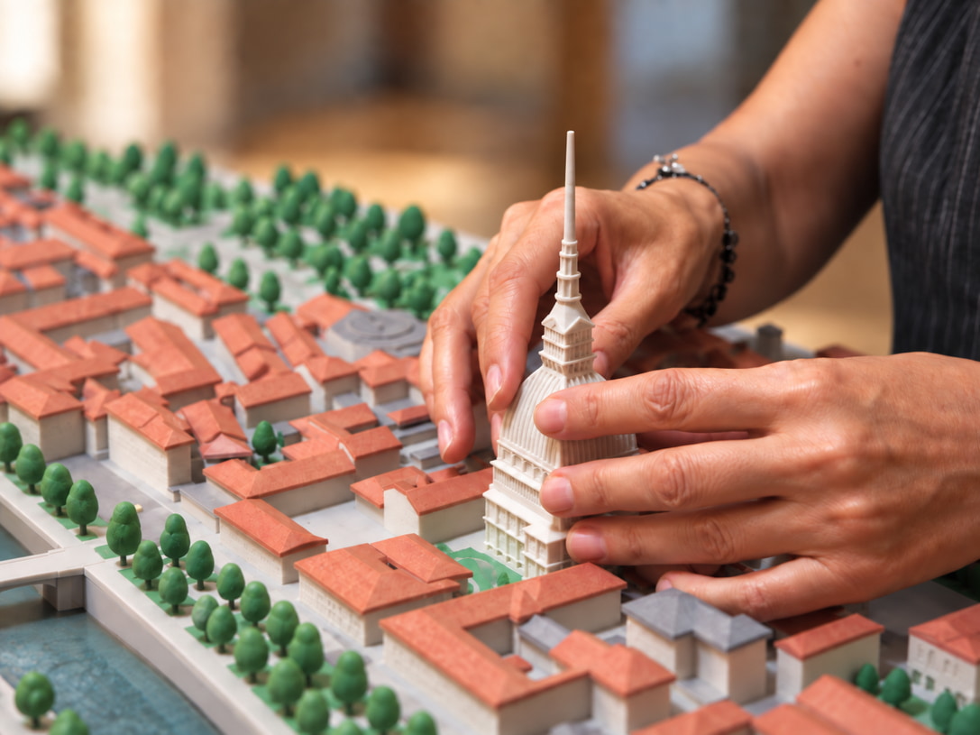 Mani esplorano un modellino tattile di Torino con la Mole Antonelliana